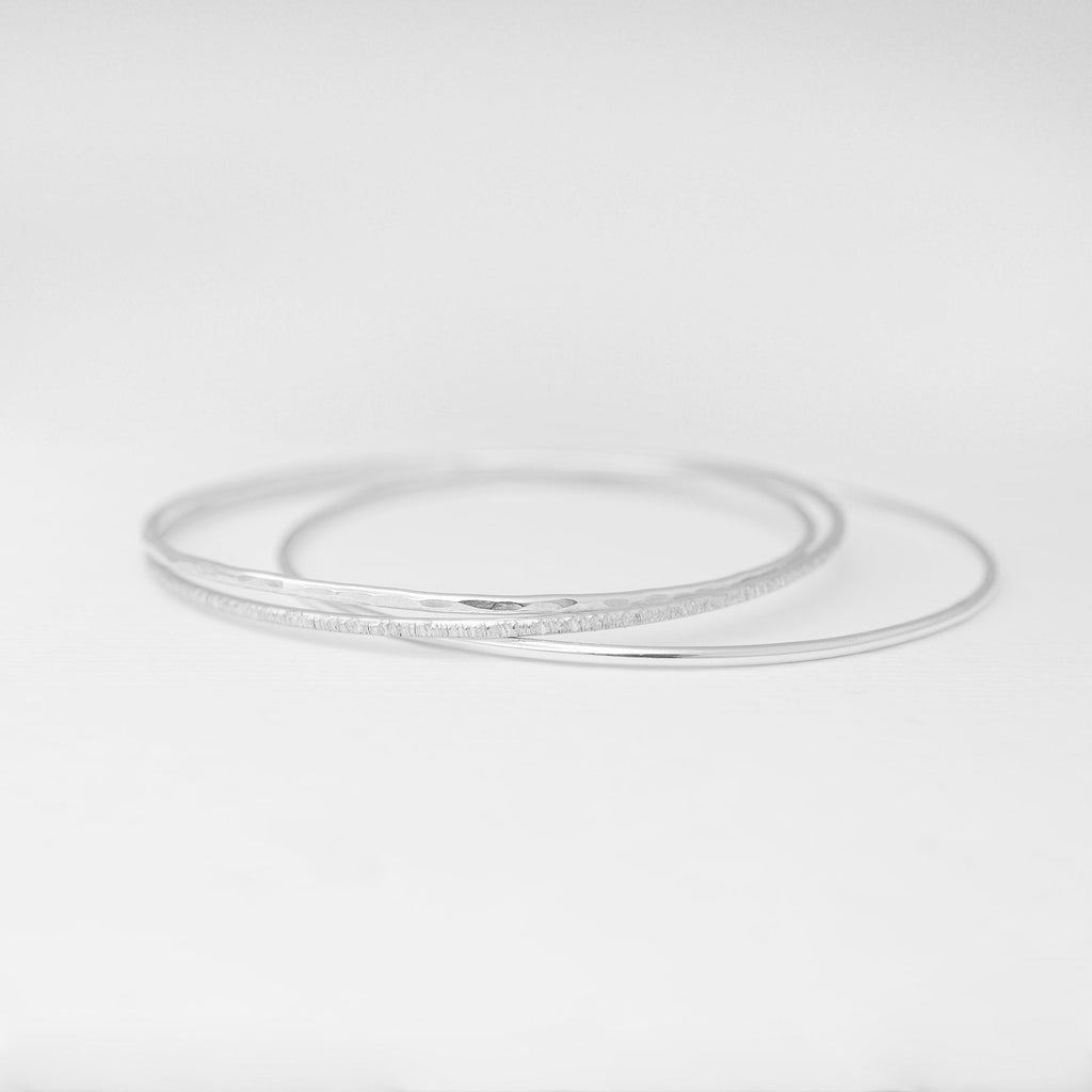 Minimalist handmade sterling silver stacking bangles in smooth birch and hammered textures