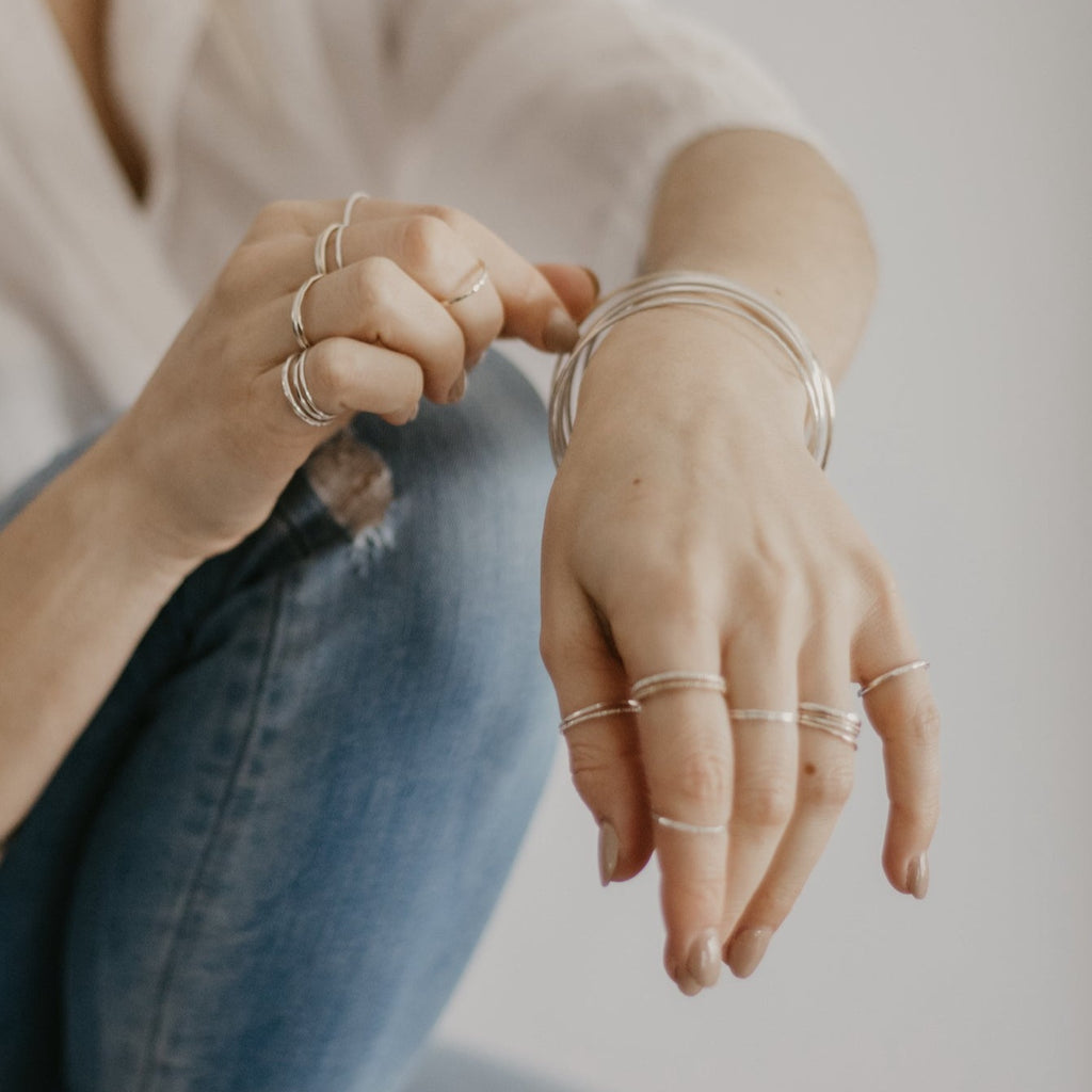 Woman wearing minimalist handmade sterling silver and 14k solid gold stacking bangles and rings