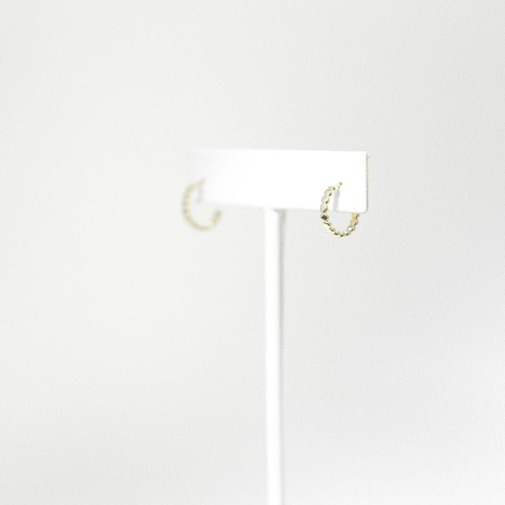 Solid 14k gold beaded mini hoop earrings on a white earring stand
