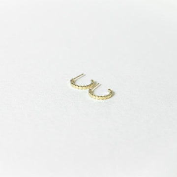 Solid 14k gold beaded mini hoop earrings on a white surface