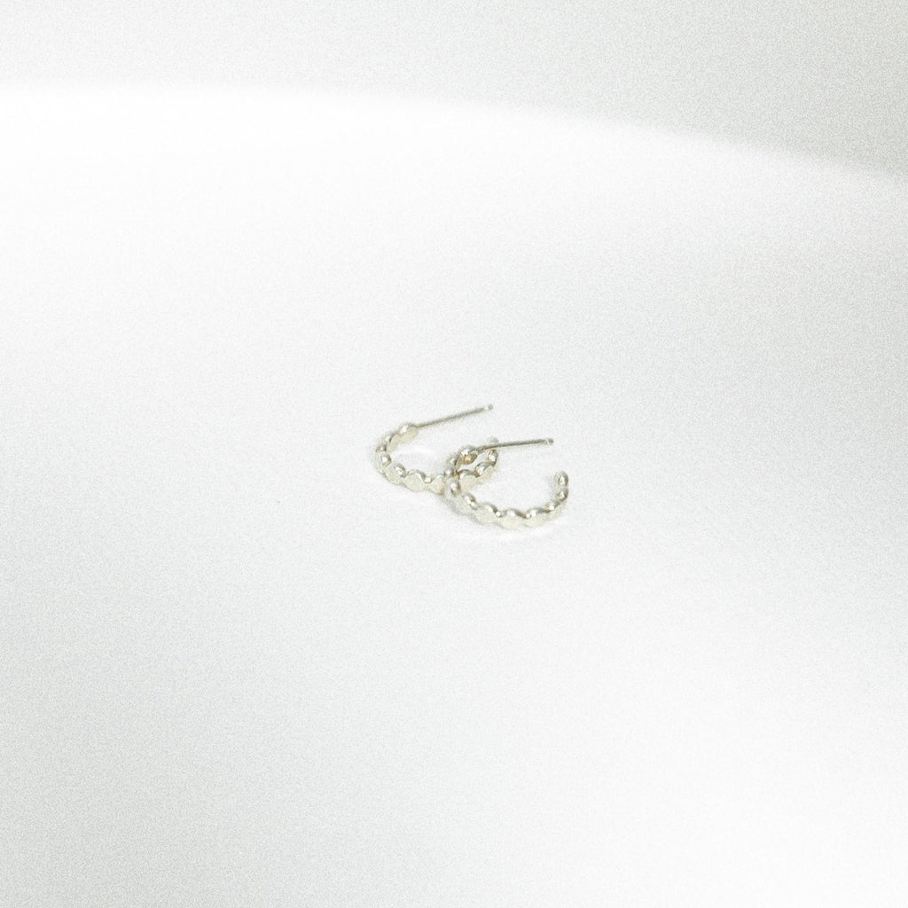 Sterling Silver beaded mini hoop earrings on a white surface