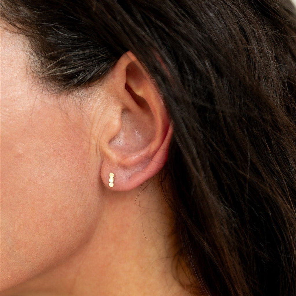 Woman wearing solid 14k gold stud earrings 