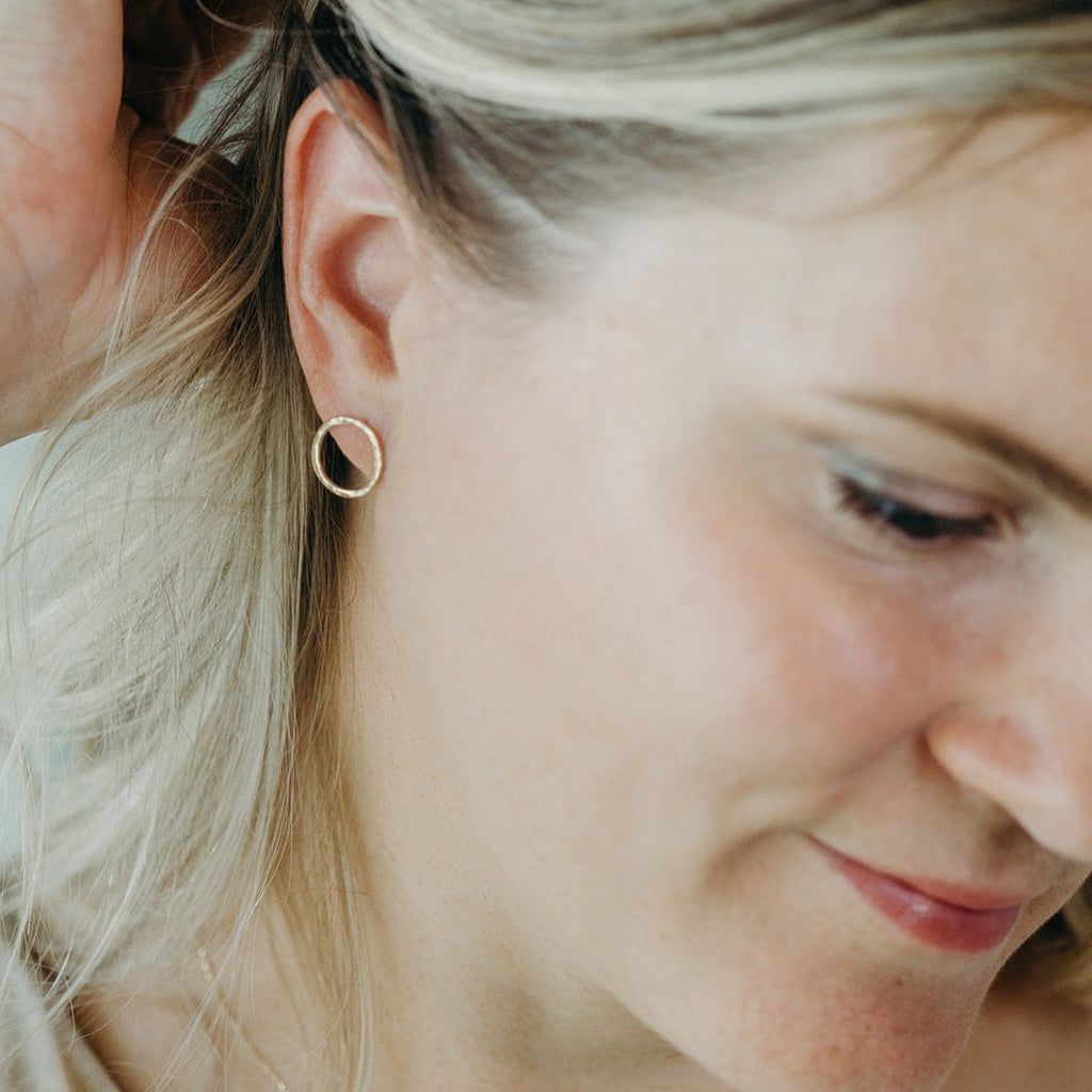 woman wearing solid 14k gold water circle stud earrings in size medium