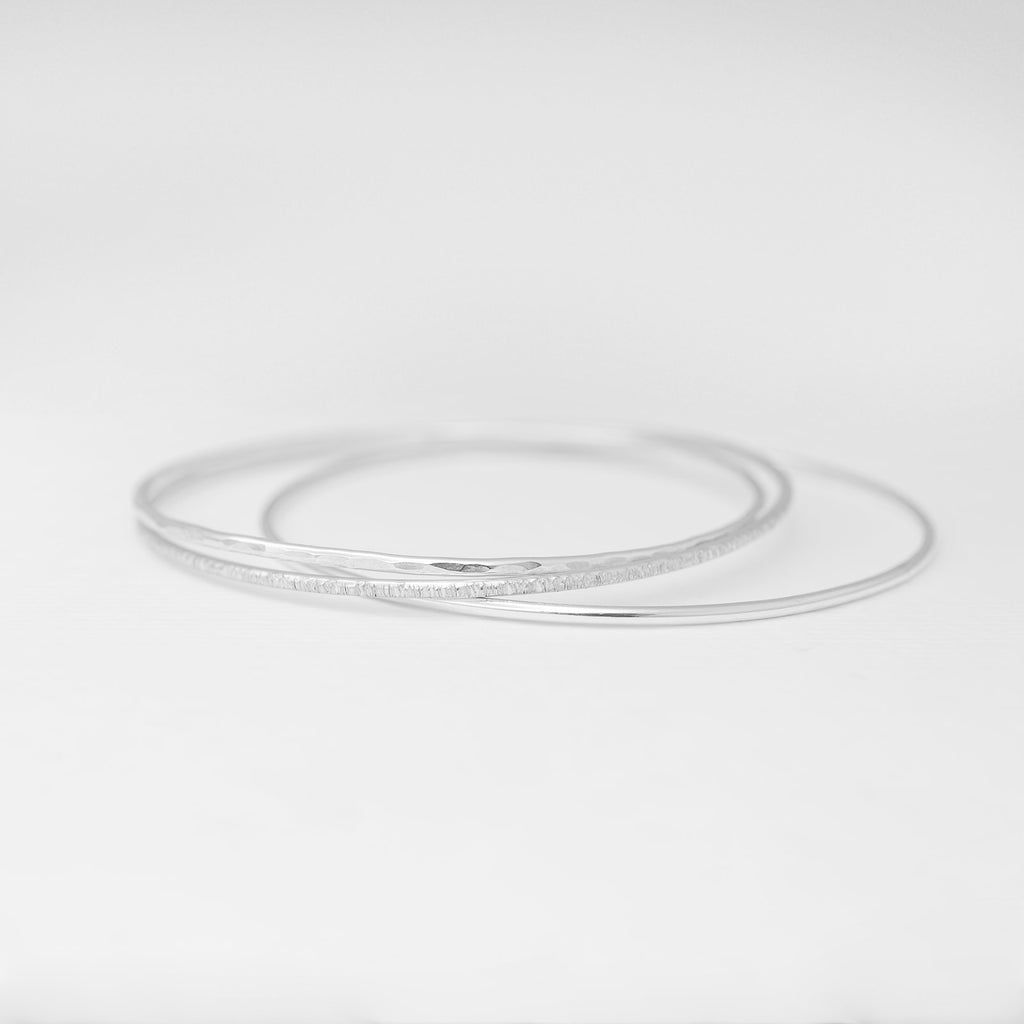 Minimalist handmade sterling silver stacking bangles in a smooth birch and hammered texture